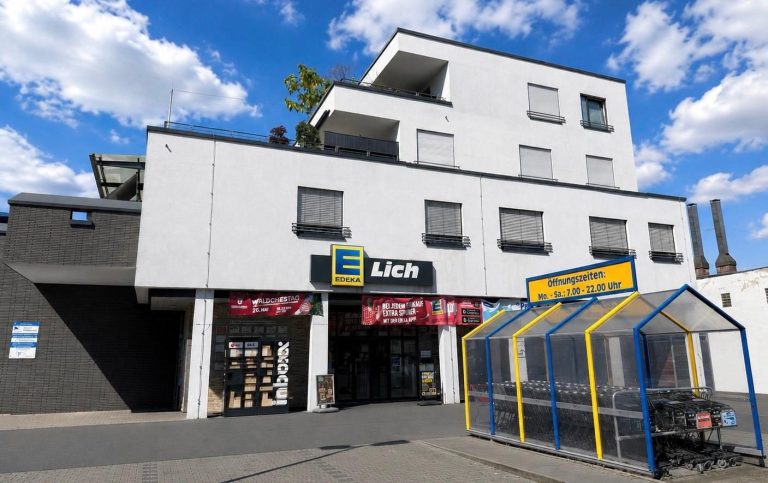 Fassade eines Geschäfts mit großem Edeka-Lich-Schild und bunten Wandmalereien.